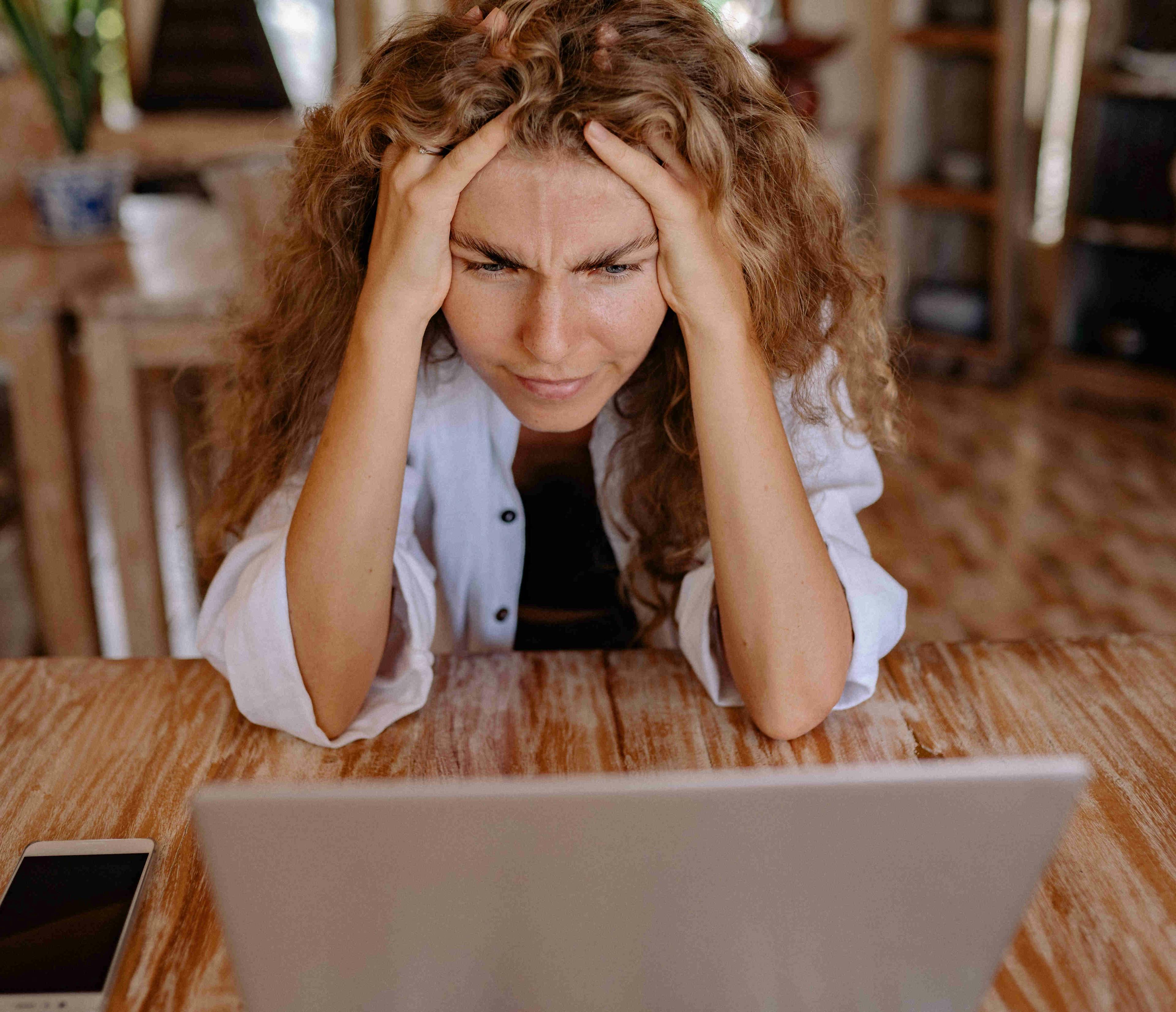 A straight on shot of a women visibly frustrated while working on her computer.
